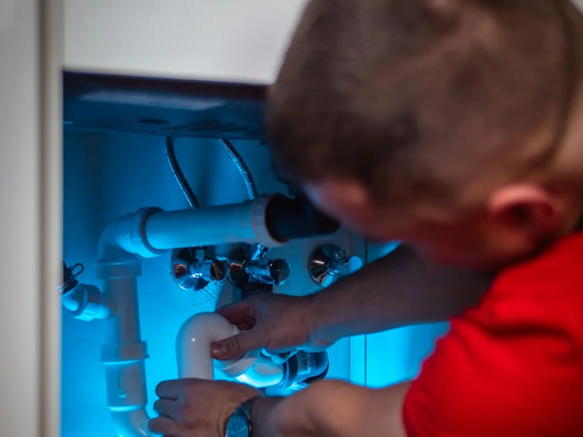 Technician repairing the connections under a water heater