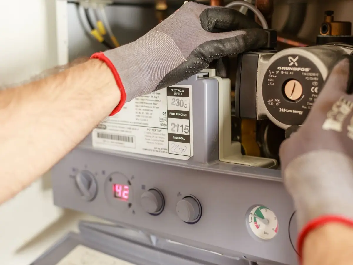 Gloved technician adjusting the controls and circulator on a heating unit