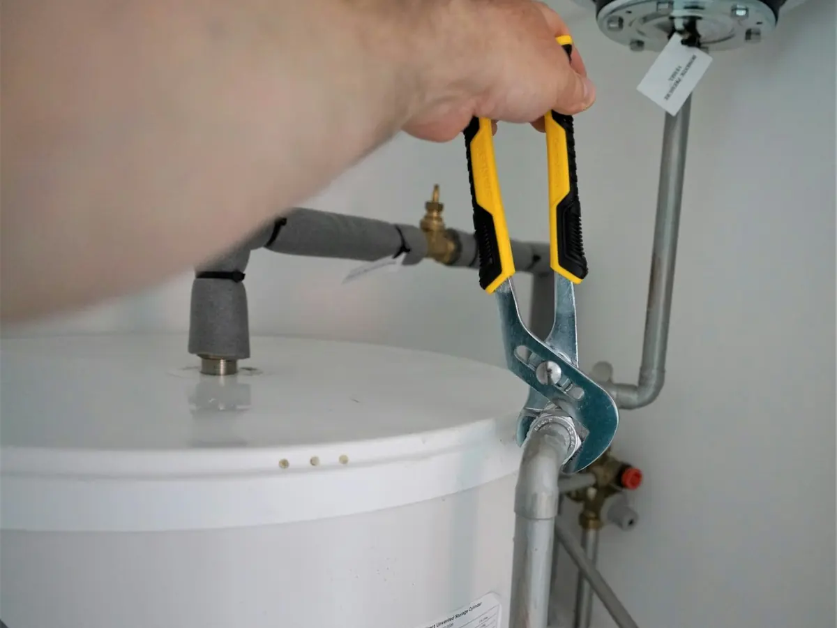 Technician checking the fittings on top of a residential tank water heater