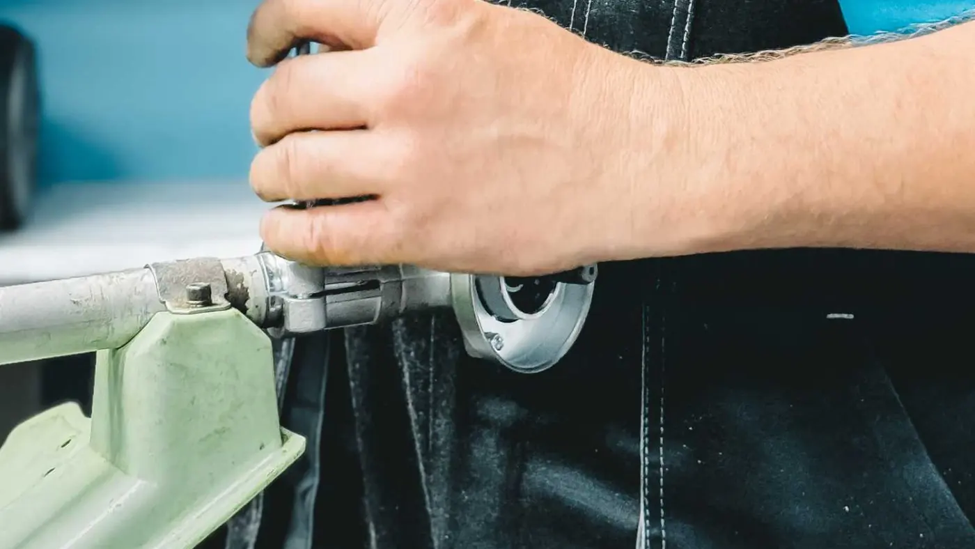 Plumber in work overalls tightening a pipe fitting with a wrench
