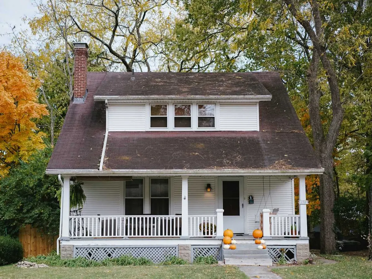 Classic white house with a front porch surrounded by autumn trees